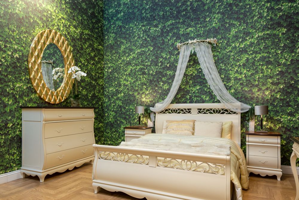 Bedroom wrapped in ivy-green foliage wallpaper with a cream bed, sheer canopy and gold-framed round mirror